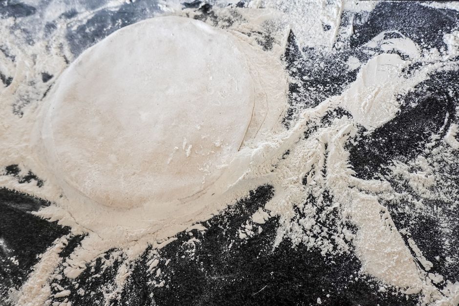 Top view of raw pizza dough on a flour-covered counter, perfect for Italian culinary themes.